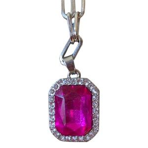 Raspberry colored pendent surrounded by clear stones on a silver tone chain